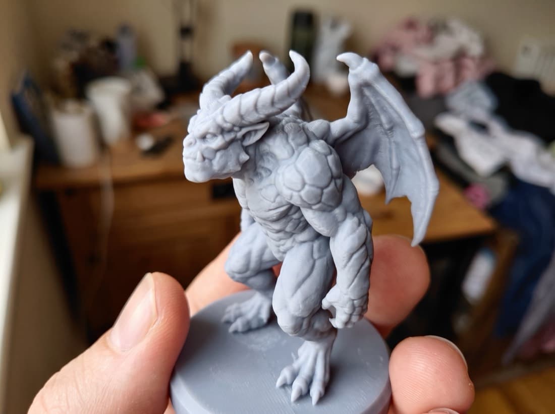 Winged creature miniature held between two fingers, layer lines visible